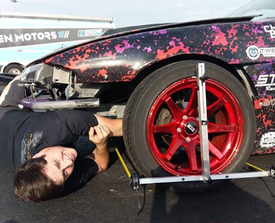 Wisitech's custom WooCommerce platform solution for QuickTrick Alignment handling complex product variations, shown with a mechanic working on a race car.