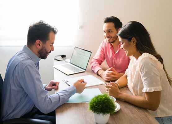A small group of three people engaged in a casual but focused discussion around a table, symbolizing business consulting, process analysis, and collaborative strategic sessions.