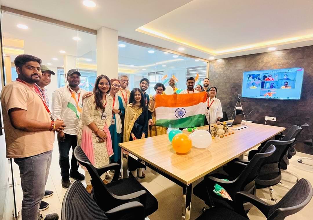 Team members posing together near a decorated conference table during the Independence Day celebration.